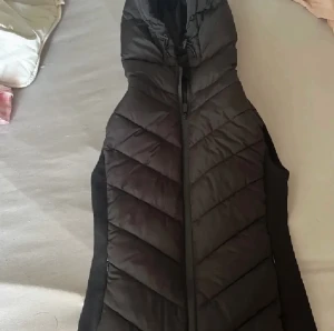 Quiltad och figursydd väst med huva från Zara - Väst från Zara, bara använd ett fåtal gånger och har alltså mycket bra skick och inga skador. Västen är i storlek S, passar bra för mig som vanligtvis har xs-s i överdelar.