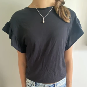 Svart t-shirt med volang - Söt t-shirt med volang ärm. Är i storlek 164 men funkar för xxs-xs. 