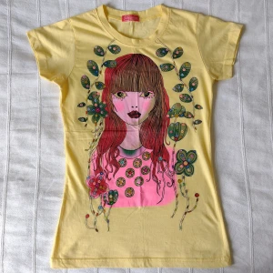 Oanvänd gul topp/t-shirt med tryck och paljetter - storlek XS/S - Mjuk och stretchig topp med skitfett färgglatt tryck och paljetter. Köpt utomlands och är oanvänd. Passar storlek XS och S skulle jag säga. 