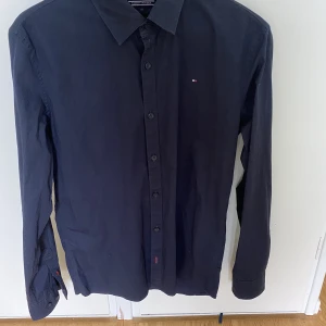 Tommy Hilfiger Skjorta - Mörkblå Tommy Hilfiger, använd väldigt få gånger. Storleken är 176 men den passar XS! Nypris 800 Mitt pris 350kr, går att diskutera!