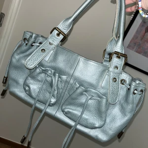 Cool väska - Säljer denna as coola vintage ljusblå/turkosa typ metallic väskan med coola detaljer som är köpt i frankrike🫶🏻 Man får plats med väldigt mycke och den har massa olika fack osv! Använd fåtal gånger av mig men jättebra skick! Köparen står för frakt