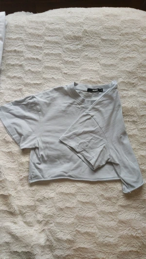 Ljusblå croppad t-shirt  - Ljus blå crop top. Vit/ljusblå/grå. Oanvänd utan tagg. Längd: 36cm. Finns också i ljus brun
