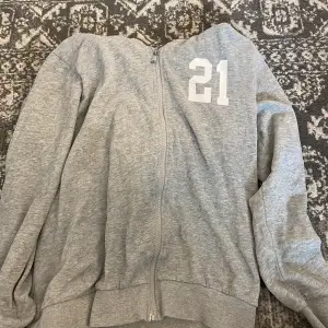 En grå zip up hoodie med ett tryck på och vita snören. Älskar den men kommer inte till användning💌
