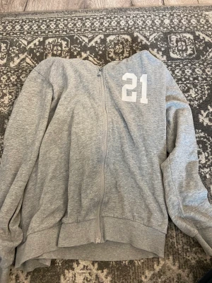 Zip up hoodie - En grå zip up hoodie med ett tryck på och vita snören. Älskar den men kommer inte till användning💌