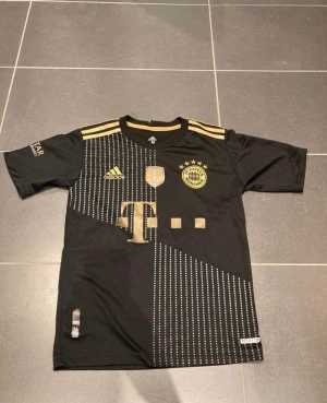 Bayern München fotbollströja  - Storlek M (sitter mer som S) Tröjan kommer ifrån när Bayern München vann Champions League och därav guldet på tröjan  