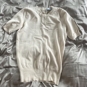 Zara topp - En beige/krämfärgad stickad t-shirt från zara. Den är i bra skick och passar båda xs och s