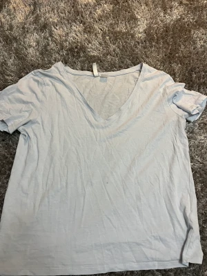 V-ringad ljusblå T-shirt - En v-ringad ljusblå t-shirt från H&M Basic i storlek S. Använd ett fåtal gånger, köparen står för frakten