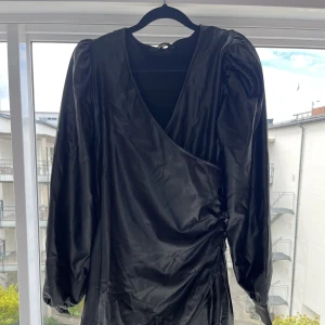 Skinnklänning - Figursydd. Sitter som en smäck. Puffiga ärmar och omlottsydd. V-ringas. Kort. 