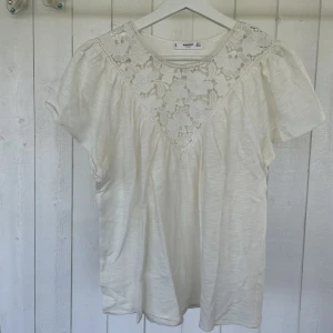 Blus - En snygg blus i gräddvit färg från Mango, med ett virkat mönster på bröstet. 