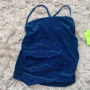 Glittrig fest topp - Glittrig blå festtopp med rutching på sidorna och låg rygg