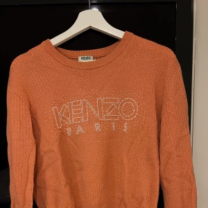 Finstickad tröja från Kenzo - Långarmad kenzo tröja, texten kenzo i vita pärlor. Använd fåtal gånger, i mycket fint skick.  Storlek: S Färg: Aprikos  Nypris cirka 2000 kr 
