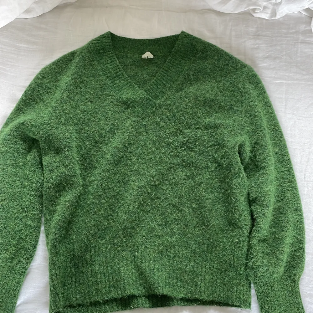 Grön stickad tröja med v-ringning från Arket. Använd endast 1 gång och i nyskick. Materialet är alpacka och ull. Köparen står för frakten.. Stickat.
