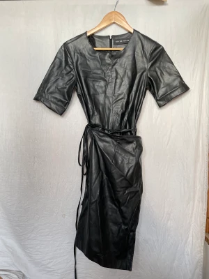 Skinnklänning - Cool skinnklänning som bara är använd några gånger. Wrapmodell med långa snören som går att anpassa efter önskan. Passar dig som har xs/s i storlek.