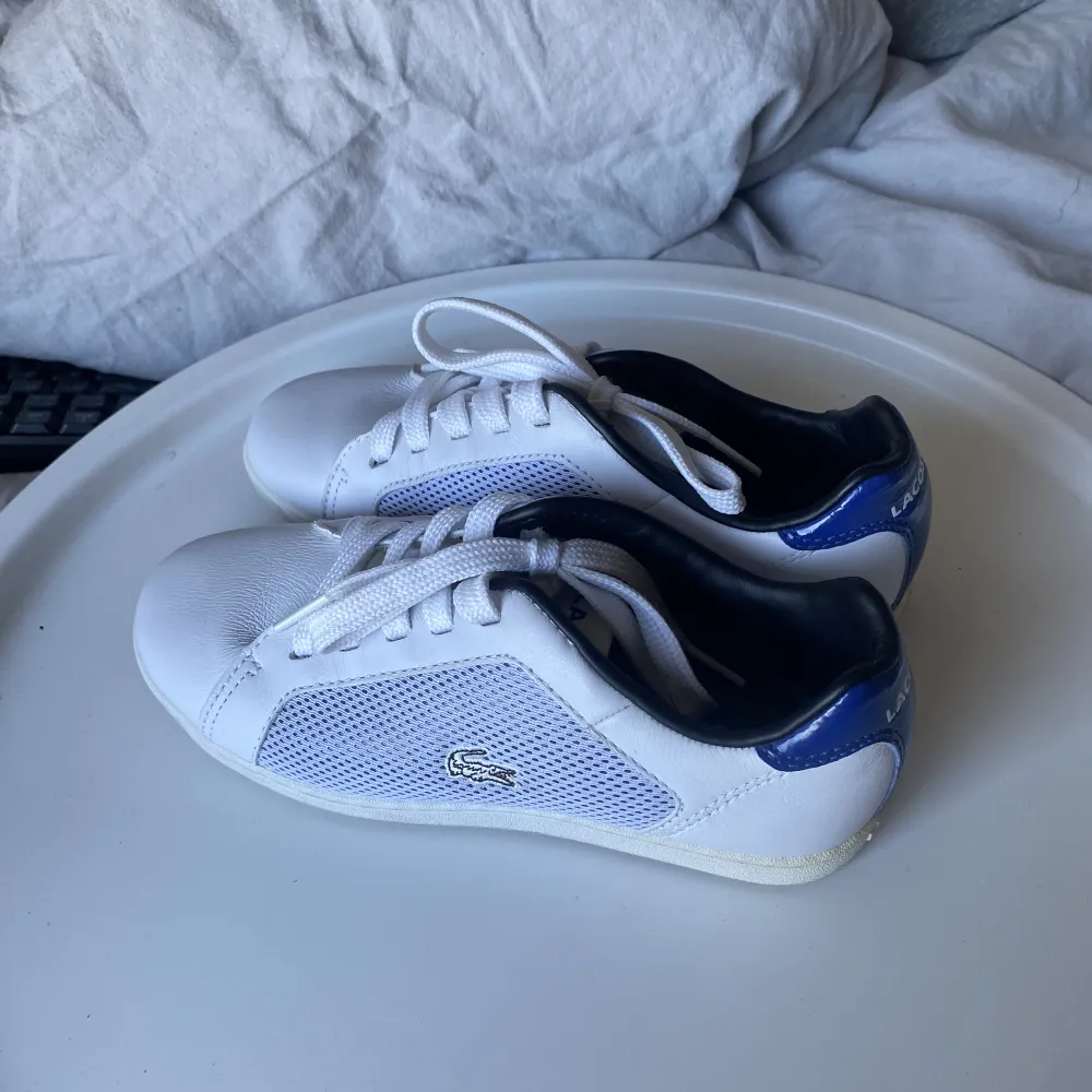 Lacoste skor med snygga blå detaljer. Andvända Max 3 gånger då det var försmå för mig. Skor.