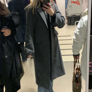 Kappa - Väldigt snygg mörkgrå kappa från HM, strl 34 i väldigt fint skick! Är i en rätt lång modell och sitter såhär på mig som är 166cm :) Nypris 1000 kr