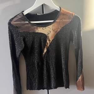Snygg svart tröja med bruna mesh detaljer över bröst och armar