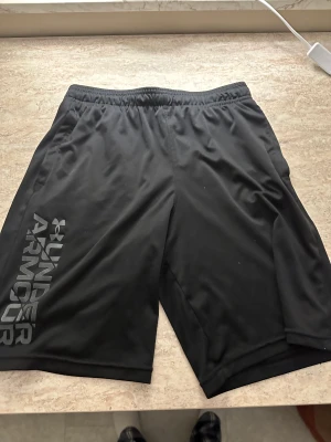 Under armour shorts - Under armour shorts. Säljer på grund av att jag växte hur dom. Bra skick förutom ett hål i vänsterfickan så det går inte att använda den