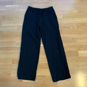 Svarta linnebyxor storlek 146/152 - Ett par svarta linnebyxor i storlek 146/152. Byxorna är i fint skick. Vi har tagit ner sömmen nertill lite och sytt om för hand för att byxan skulle bli längre. Innerbenslängden på dem är ca 67-68cm nu. Material: 55% linne, 45% bomull.