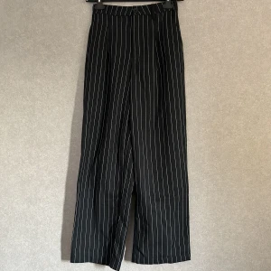 randiga kostymbyxor - svarta randiga byxor från h&m. köpta second hand men aldrig använda av mig. lite noppriga vid midjan men inget som syns.