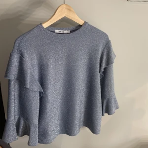 Glittrig Festtröja  - Säljer denna fina glittriga tröja från nakd som är trekvartsärmad då den aldrig kommit till användning❤️inga defekter!! Storlek xs men passar mig som brukar ha s/m❤️nypris 399kr