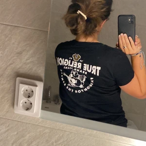 True religion T-Shirt - Säljer denna t shirt. Den är typ i nyskick. Den har en QR kod som bevisar att den är äkta. Den är i storlek XL men passar allt ifrån S-XL beroende på hur tajt man vill ha den💕tror originalpris är ungefär 800kr, ge gärna prisförslag!