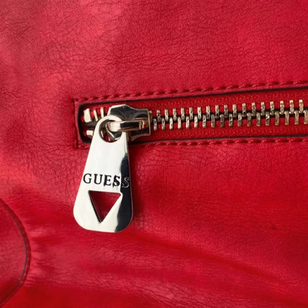 Röd guess handväska, långt band finns, ”keychain” hänger på ena handtaget 3 innefickor, 1 bak och 1 fram Silver detaljer Dust bag medföljer. Väskor.