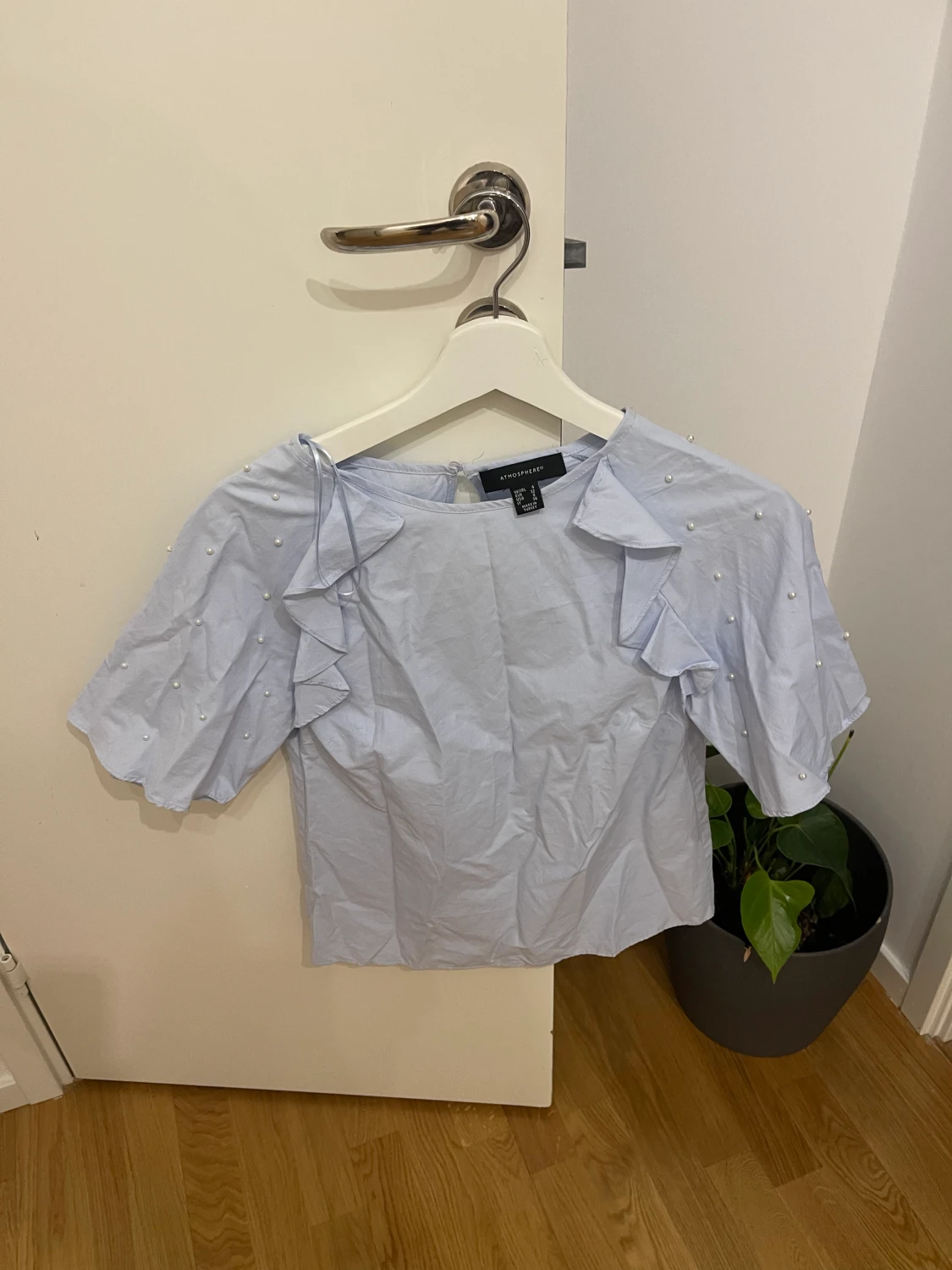 Ljusblå topp med vita pärlor på ärmen