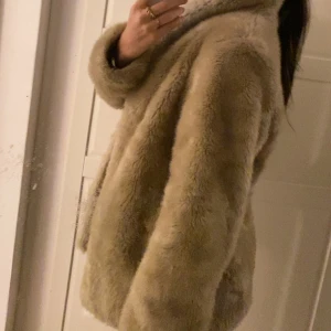 Faux fur jacka  - Intressekoll på denna jacka i fejkpäls. Från ”hennes” kollektionen köpt second hand. Stängt med knappt och ett bälte som medföljer . Säljes pga flytt. Pris kan diskuteras vid snabb affär!