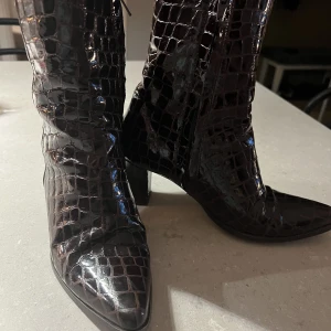 Flattered stövletter - Flattered stövletter med krokodilmönster/lack. Klädd klack. Fint skick. Nypris 3295kr