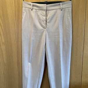 Beige-rosa kostymbyxor strl 42 - Aldrig använda, ändrar färg efter vad man sätter till. Mått: midja 44, längd 99. Strl 42