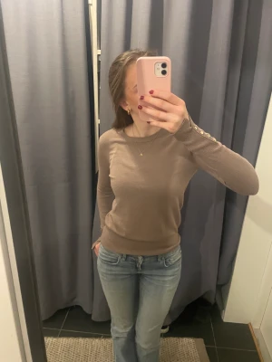 Tröja med knappar - Tröja i lite tjockare material. Tyvärr har sömmen gått upp lite vid ena armen (se bild 2), men det går enkelt att sy ihop igen. Dessutom är tröjan lite nopprig vid ett parti (se bild 3)