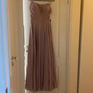 Balklänning - En jättefin balklänning från proms and wedding med knytbar ryg och en slit i st 40/42.  Helt ny och prislappen är kvar!!  Fin lite gammelrosa/ljusrosa (dusty rose) färg.  Ordinarie pris på 2000kr.  (Köparen står för frakt) Passar folk på 165cm/170cm🌟