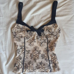 Superfin korsett med broderat mönster - Säljer denna såå fina korsett med broderade blommor på sig💕 Strl s på lappen men är förliten för mig som brukar ha s så skulle säga att den är mer en xs. Den har ett litet hål längst ner vid dragkedjan (bild 3) som man lätt kan laga/sy ihop.💗💗💗