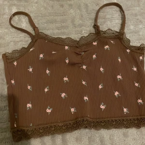 Brun topp  - Toppen är brun och i storlek xs. Den har används 1 gång och är croppad. Toppen har band som går att justera. 