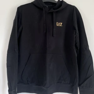 EA7 Emporio Armani hoodie M - Säljer denna hoodie som är använd endast 1 gång, i nyskick! Nypris 1085kr. Den är svart med guldiga detaljer. Skriv vid frågor eller fler bilder🖤