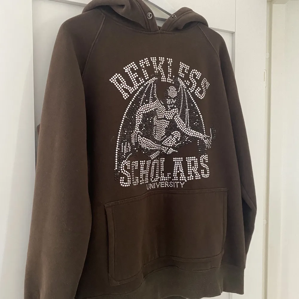En snygg brun Reckless Scholars hoodie i strl L🤎Några stenar har lossnat vid bokstäverna annars är den i gott skick! Skriv för fler bilder. Hoodies.