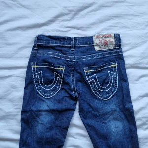 True Religion Jeans  - Fina jeans från True Religion! Riktigt bra skick med fina detaljer och brodering. Köpta secondhand, osäker på äkthet, därav priset. Strl 28 Mått: Ytterbenslängd: 93 cm Innerbenslängd: 74 cm Midja tvärs över: 34 cm