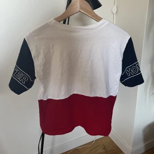 T-shirt  - T-shirt från Hollister. Blå, vit och röd med testen Hollister på armarna. Köpt för ett tag sedan men inte sliten.