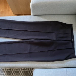 Kostymbyxor  - Snygga kostymbyxor. (med stora framfickor!!) Jag har storlek 38 i byxor och dessa är ändå för stora för mig. (Både långa och stora i midjan) 