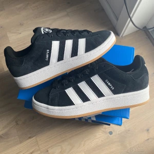 Adidas Campus 00s ”Black White Gum” - Säljer dessa svarta Adidas Campus 00s ”Black White Gum”. De är helt nya och oanvända. Köpta ifrån Zalando och självklart äkta. Finns i storlek 38 men andra storlekar går även att lösa. Swish föredras men går även att köpa direkt i appen.