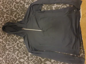 Träningshoodie H&M i fint skick - En grå träningshoodie i fint skick. Den har ficka där bak, rundad kant och reflex på ena armen. 
