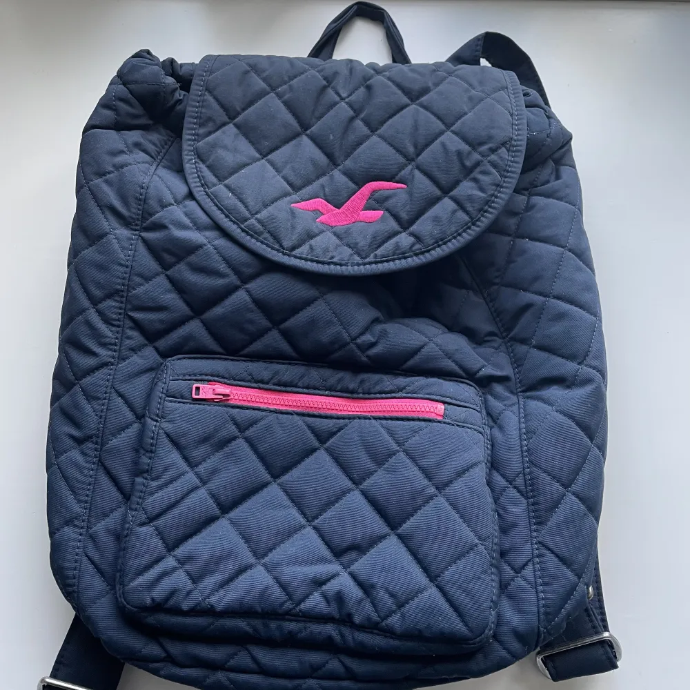 Mörkblå ryggsäck från Hollister med rosa detaljer, väldigt rymlig och i mycket bra skick . Väskor.