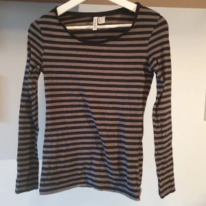 Randig tröja  - Randig tröja i svart och grått från H&M. Tight passform och långa ärmar. Lite nopprig på vissa ställen. 
