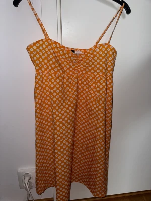 Blommig sommarklänning - Säljer denna super söta orangea klänning med vita blommor. Klänningen är i xs och den har nu blivit för kort för mig💞✨  Den kommer ifrån divided - HM. Dragkedja på sidan och ihopdraget mellan brösten👌🏼✨💞