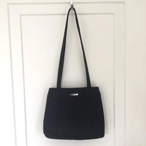 Väska i mörkblå/svart färg. Det är en liten/ mellanstor väska som sitter perfekt på axeln. Höjd-23cm  bredd-28 cm