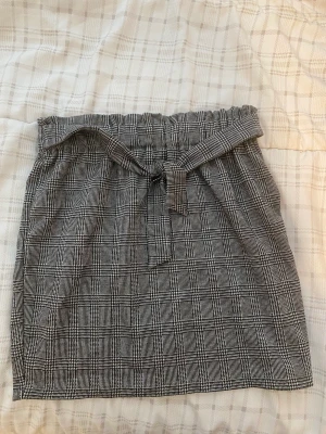 Kjol, plädkjol - Supersöt grå plädkjol med en knytdetalj, den är i storlek 146/152 men passar mig som är kortare vuxen (155cm). Den sitter som en XS ungefär. Aldrig använt denna innan så den är i superbra skick. 