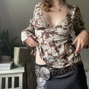 Brun tröja med pärlor - Säljer min superfina bruna tröja från Lindex. Den har detaljer av glaspärlor och spets längst med nacken, och ett band runt midjan. Saknas dock ett par pärlor och det finns lösa trådar, samt ett hål på axeln. 