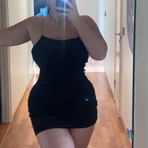 Svart klänning  - Skitsnygg svart stretchiga klänning med diamantband och korsade i rygg