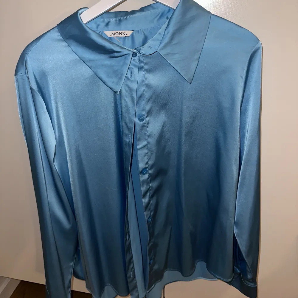 Skjorta i blått glansigt tyg. Använd vid 1 tillfälle. Jättefin, säljer för att jag inte riktigt passar i färgen! Skönt luftigt material. Blusar.