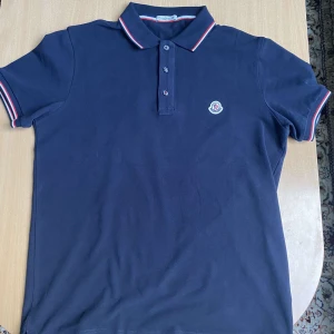 Moncler Piké - Mörkblå Mocler Piké i storlek M. NFC finns. Jättebra kvalite. Sitter bekvämt och passar jätte bra till sommaren. 